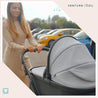 Mother pushing child in the Nebula Cool Grey carry cot on pushchair.